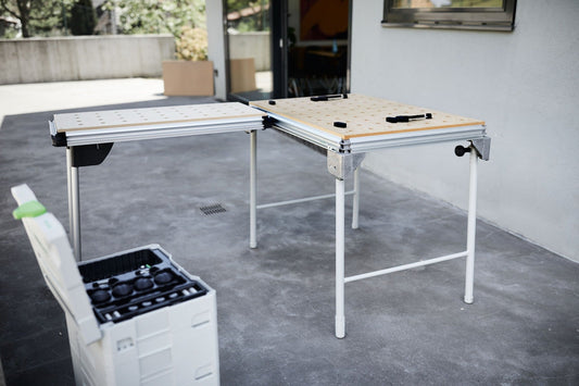 Festool Tisch TSB/1-MW 1000 mit Lochplatte und Aluprofil auf grauem Untergrund, daneben Systainer mit Werkzeugzubehör.
