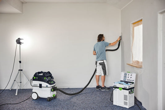 Festool Absauganlage mit Reduziermuffe beim Absaugen von Staub an der Wand während Renovierungsarbeiten