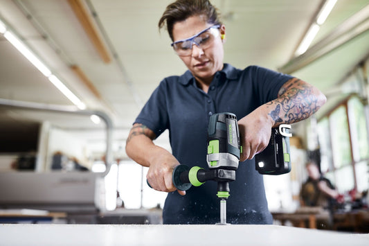 Festool QUADRIVE TPC 18/4 Akku-Schlagbohrschrauber in Anwendung beim Bohren, Handgriff mit grünem Akku sichtbar.