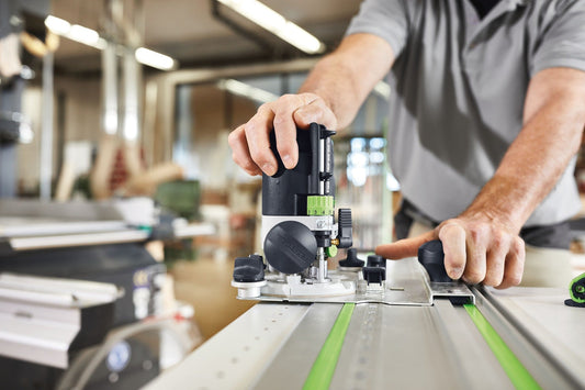Festool OF 1010 Oberfräse mit LED-Arbeitslicht beim Fräsen auf Werkstück mit Führungsschiene in Werkstatt