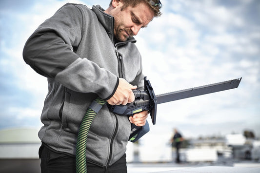 Festool ISC 240 EB Akku-Dämmstoffsäge in Anwendung beim Zuschnitt von Dämmstoffen, Arbeiter hält Säge mit ergonomischem Griff
