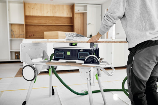 Festool CSC SYS 50 EB-Basic Akku-Tischkreissäge auf Arbeitstisch mit Schiebeschlitten und Parallelanschlag beim Sägen von