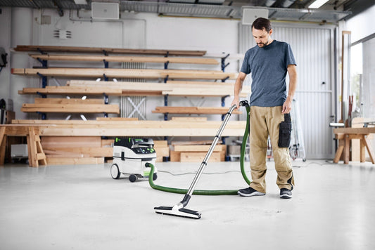 Festool CT Saugschlauch mit Absaugmobil in Werkstatt, Handwerker saugt Betonboden mit Bodendüse.