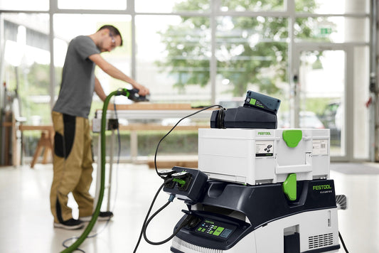 Festool CT 26 Absauganlage mit Steckdosenmodul und grünem Stromkabel, Handwerker nutzt Elektrowerkzeug in heller Werkstatt