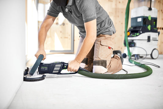 Festool Sanierungsschleifer RENOFIX RG 130 ECI beim Schleifen an Wand mit Absauganlage und grünem Schlauch