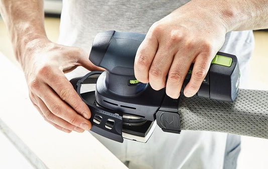 Festool DTSC 400-Basic Akku-Deltaschleifer in Händen, ergonomische Bedienung mit 18V Ergo-Akku und Bedienelementen sichtbar