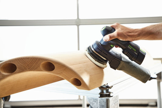 Festool Akku-Exzenterschleifer ETSC 125 beim Schleifen einer Holzoberfläche mit Schleifteller und Absaugschlauch