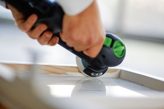 Festool ROTEX RO 90 DX Exzenterschleifer beim Schleifen auf Holzoberfläche mit grünem Schleifteller