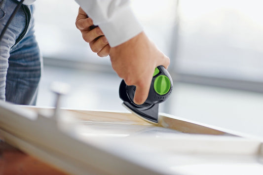 Festool Granat V93 Schleifblatt dreieckig beim Schleifen auf Holzoberfläche, grüner Klettkreis sichtbar